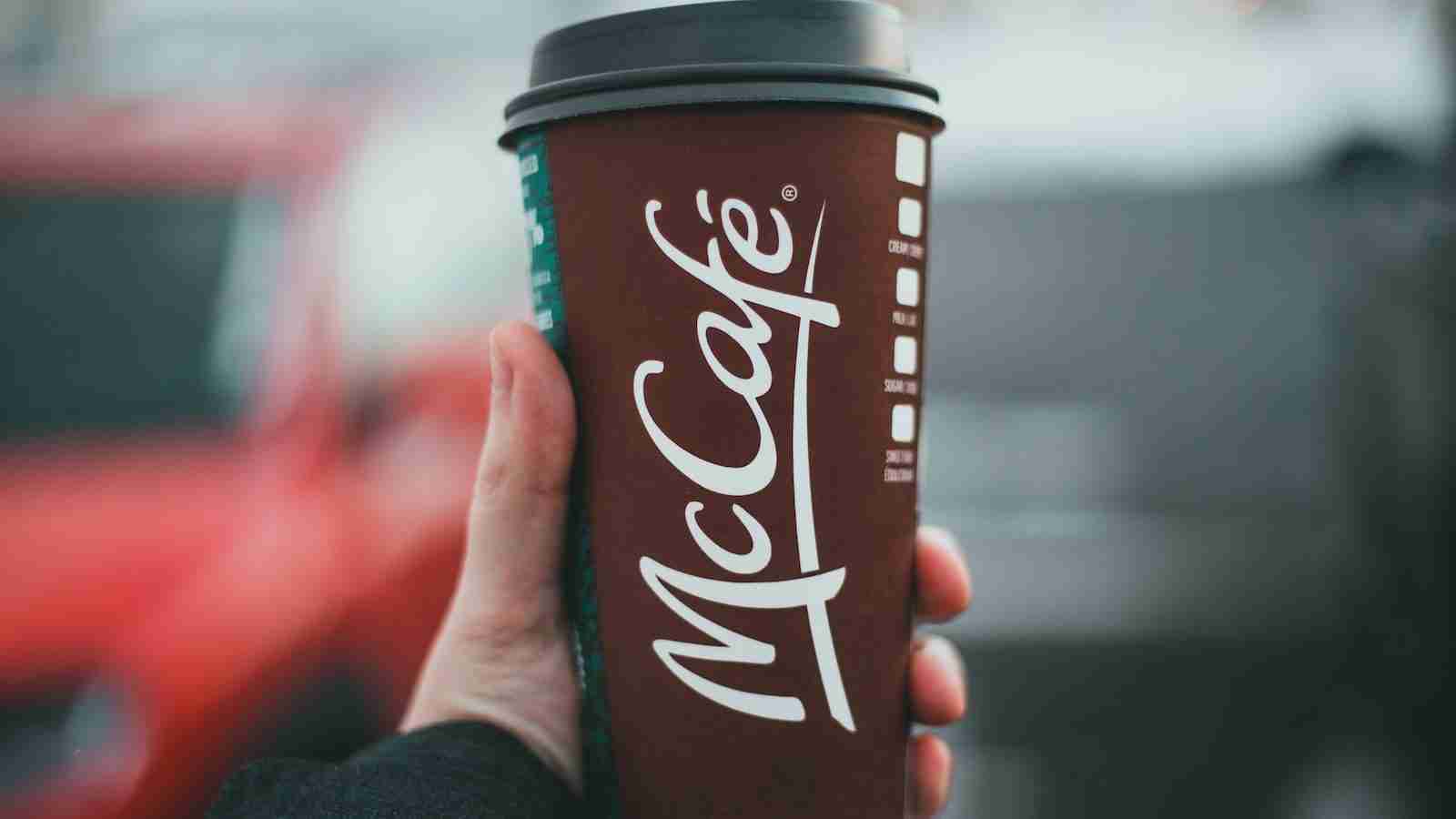 person holding red and white coca cola disposable cup