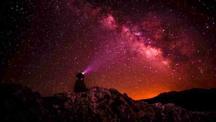 silhouette photo of person holding flashlight under milk way