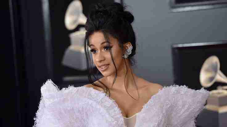 Woman in a butterfly dress with black hair and silver earrings. Fun facts about Cardi B.