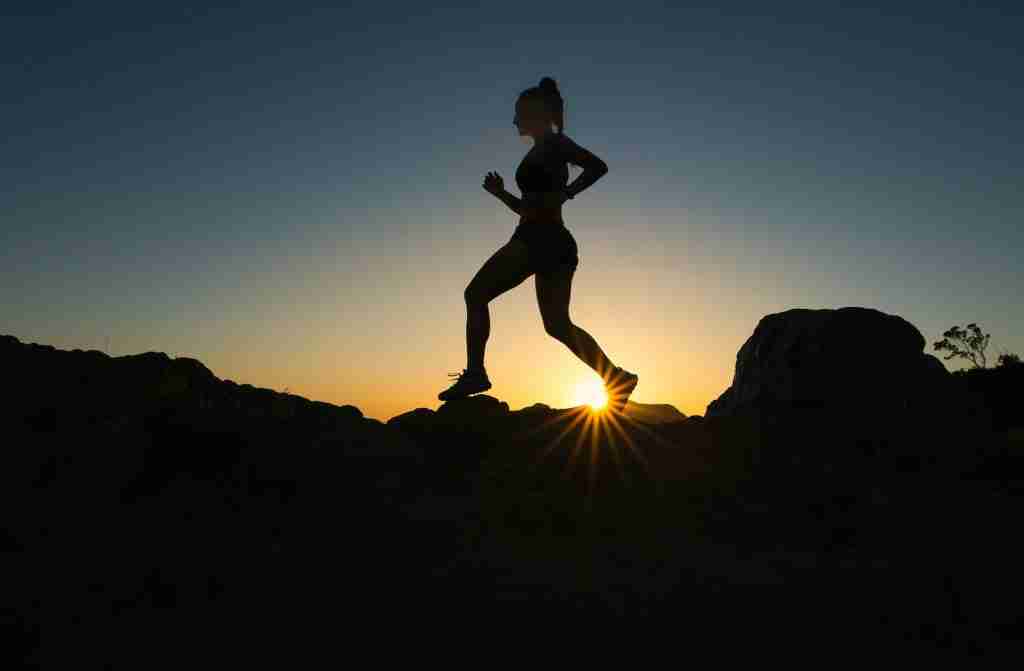 Silhouette of a man running on a rocky mountain during sunset, with a focus on fun facts about running.