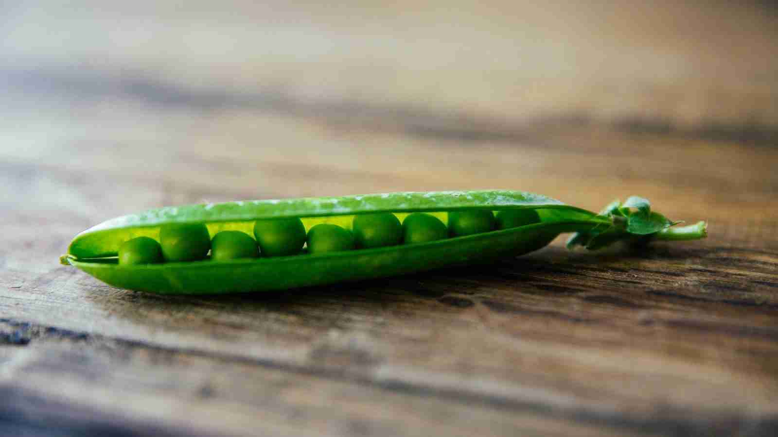 shallow focus photography of green pea on brown wooden surface