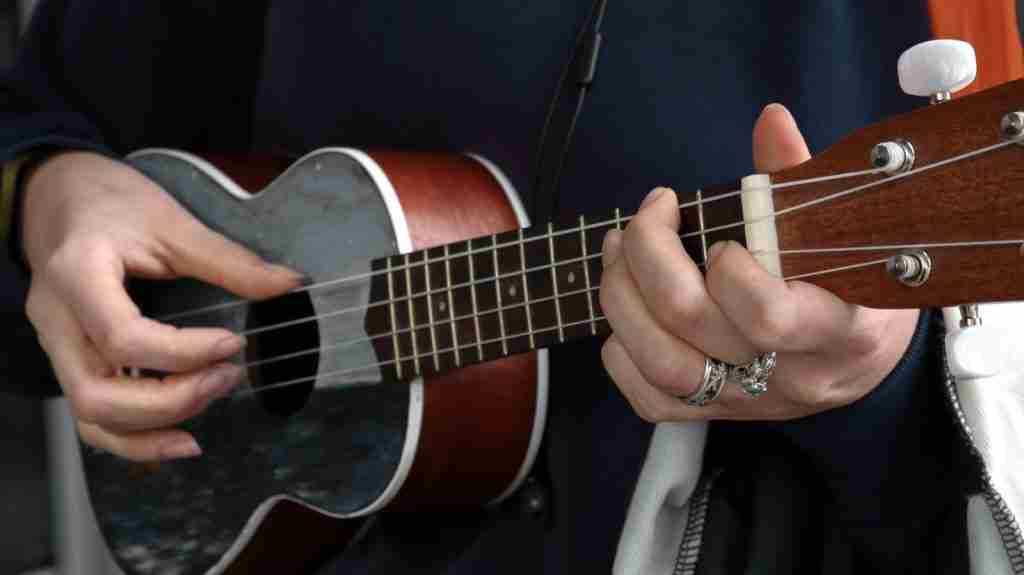 person playing red Ukulele.