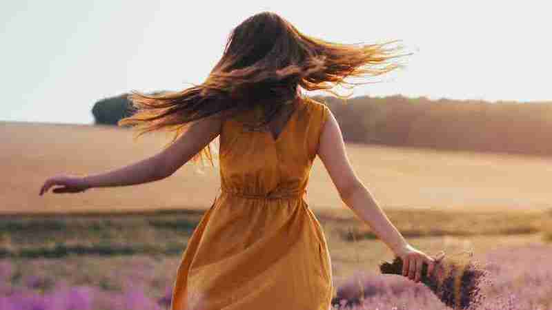 woman in yellow dress standing on purple flower field during daytime