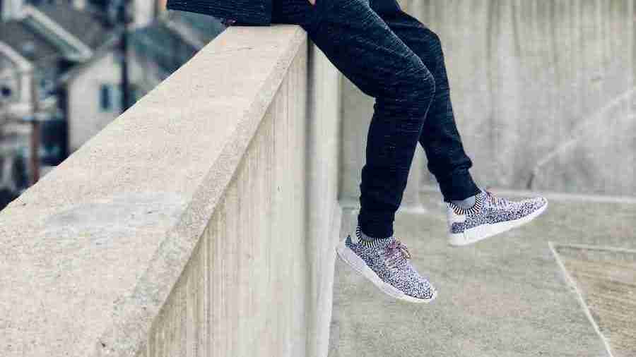 man sitting on railing while hands on pocket wearing joggers