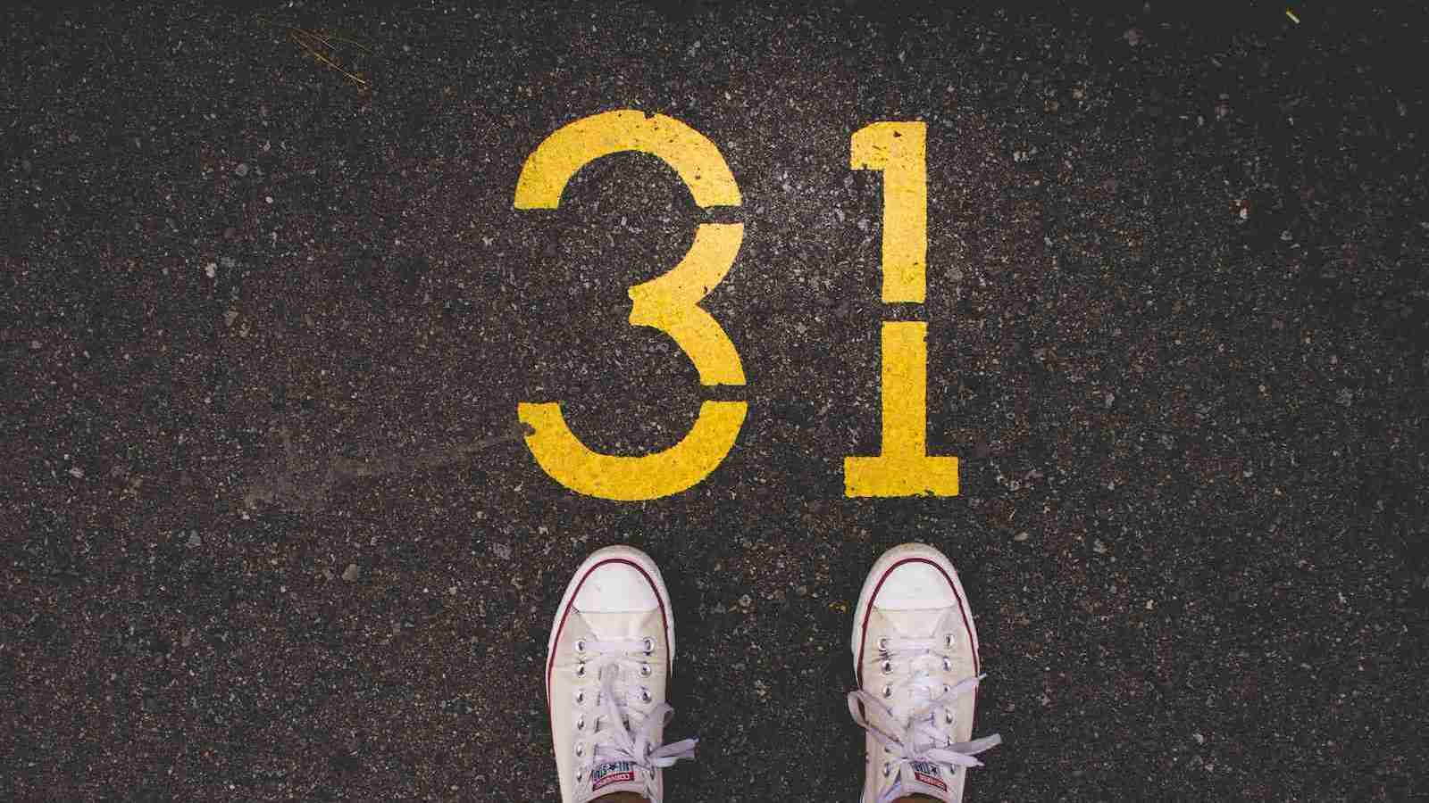 person standing beside 31 painted gray concrete road at daytime