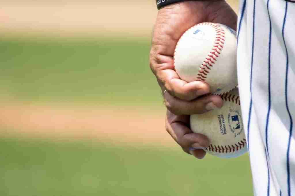 player holding two white baseballs