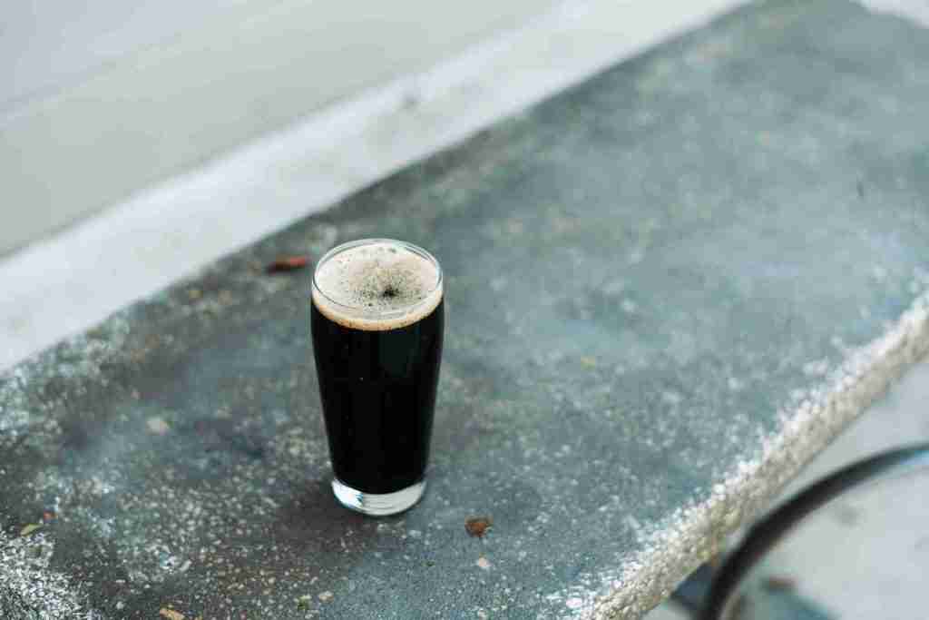 a glass of beer sitting on top of a cement bench