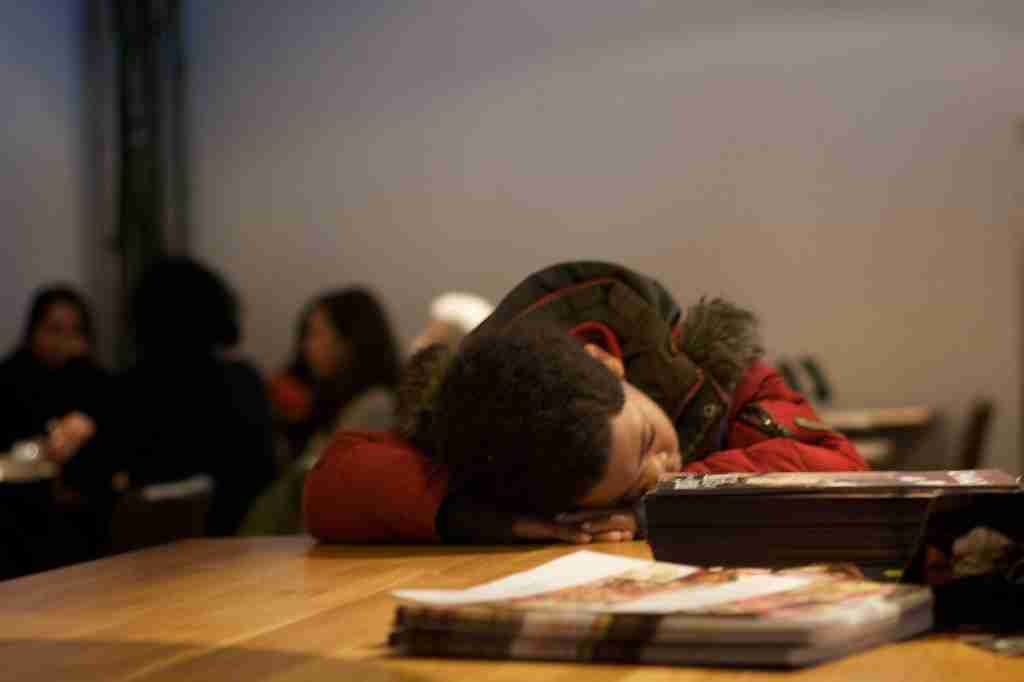 A school boy holding his head on a table