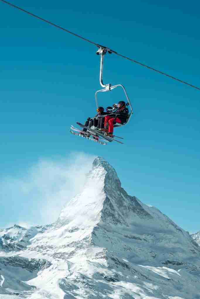 red and black cable car over snow covered mountain