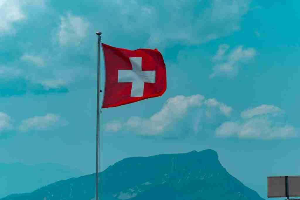 red and white cross flag on pole under blue sky during daytime