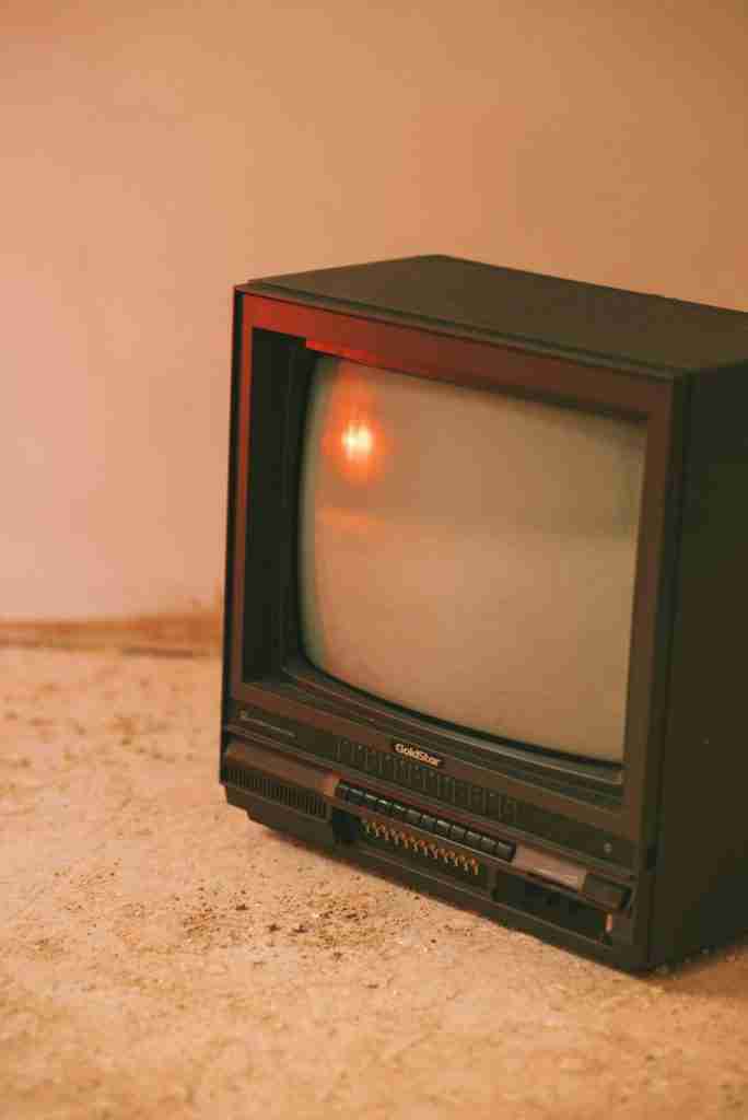 Old fashioned television set with cathode ray tube display on rough floor in house