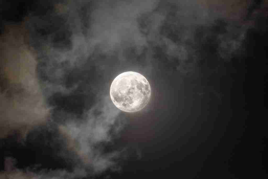 a full moon is seen through the clouds