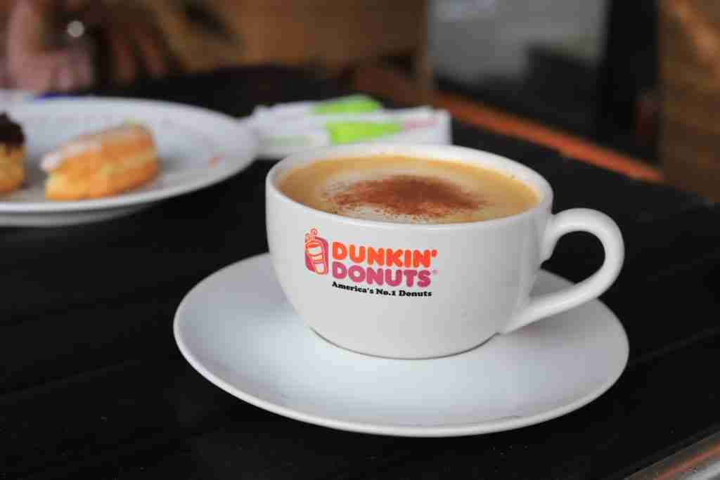 A cup of coffee sitting on top of a saucer, highlighting fun facts about Dunkin' Donuts