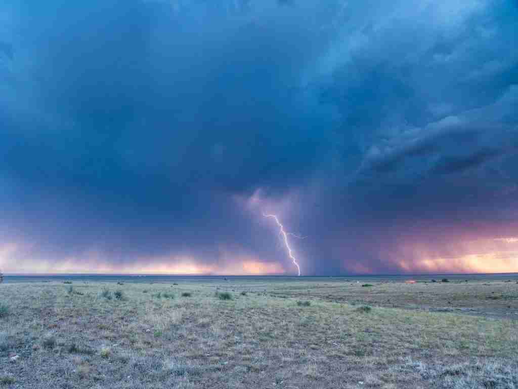 gray sand under blue sky with lightning