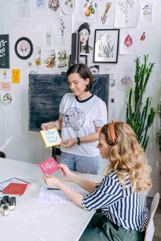 Women Holding Cards with Handwritten Lettering